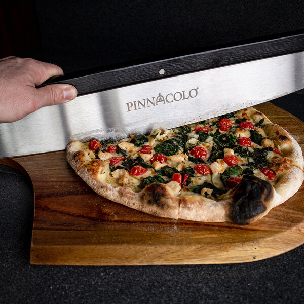 A person using a Pinnacolo rocking pizza cutter to cut a pizza.