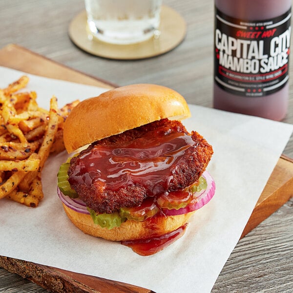 A burger and fries with Capital City Mambo Sauce on a wooden board.