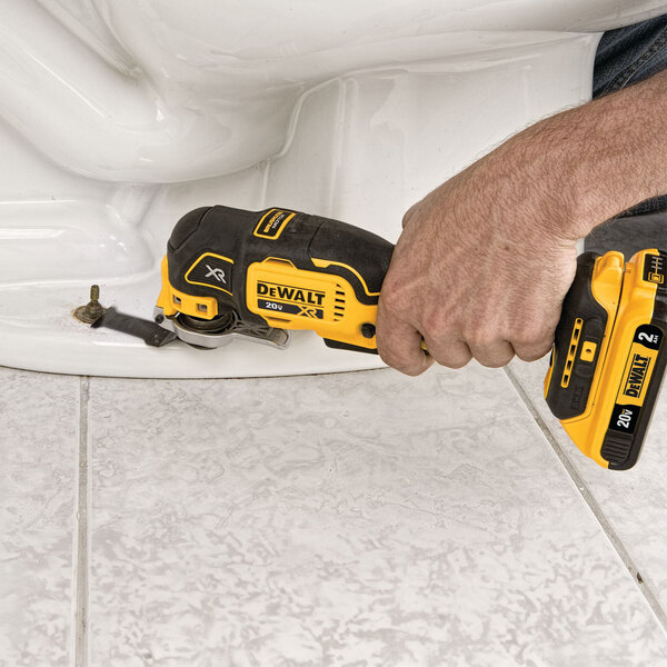 A person using a yellow and black DeWalt cordless multi-tool to fix a toilet.