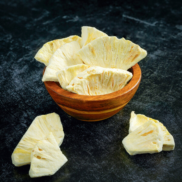 Rainforest Supply freeze-dried pineapple slices in a wooden bowl.