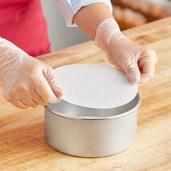 A person in gloves holding a round Baker's Lane parchment liner.