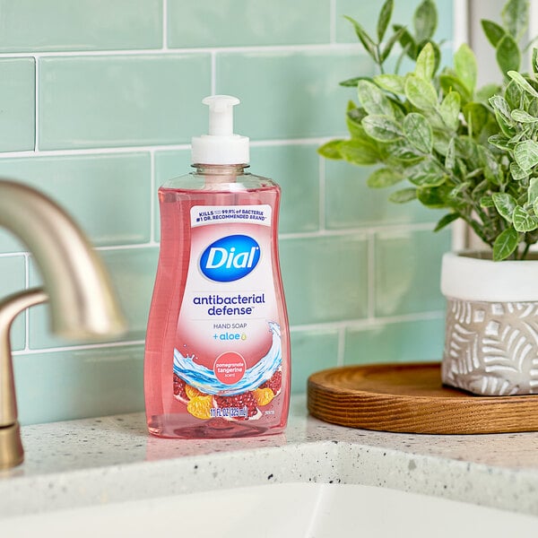 A bottle of Dial Pomegranate Tangerine liquid soap on a counter.