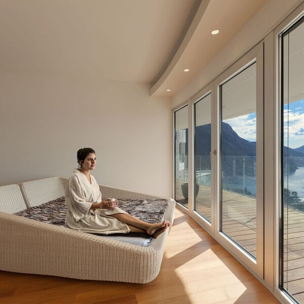 A woman sitting on a bed wearing a Telegraph Hill Stone Seersucker bath robe holding a cup of coffee.