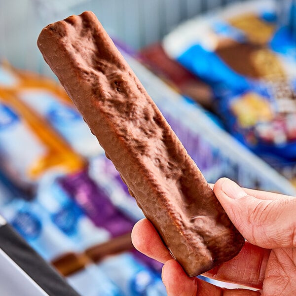 A person holding a SNICKERS Ice Cream Bar.