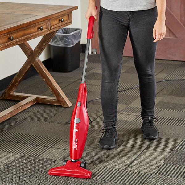 A woman using a Dirt Devil 3-in-1 upright stick vacuum on carpet.