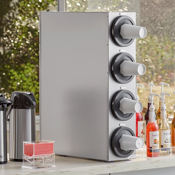 A KleanTake stainless steel cup dispenser cabinet on a counter with white cups.