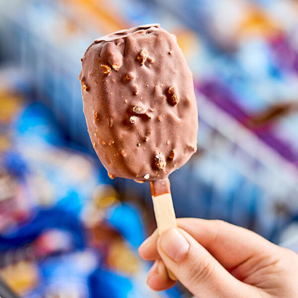 A close-up of a person's hand holding a DOVE milk chocolate and almond ice cream bar.