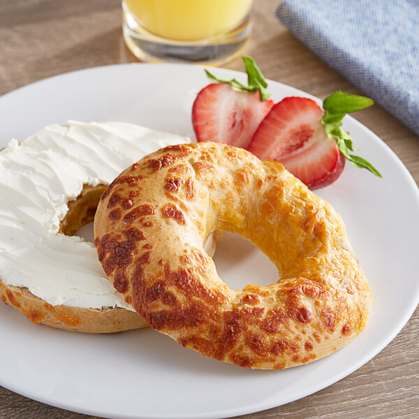 A Just Bagels Jalapeno Cheddar bagel with cream cheese on top on a plate with strawberries.