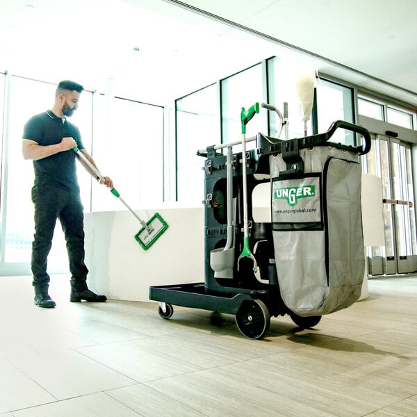 A man holding a mop and cleaning a Unger ZoneCleanRx janitorial cart.