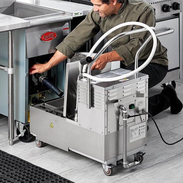 A man using a Fryclone portable fryer oil filter machine on a counter in a professional kitchen.