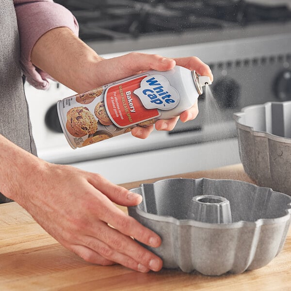 A person spraying a white cap on a baking dish.