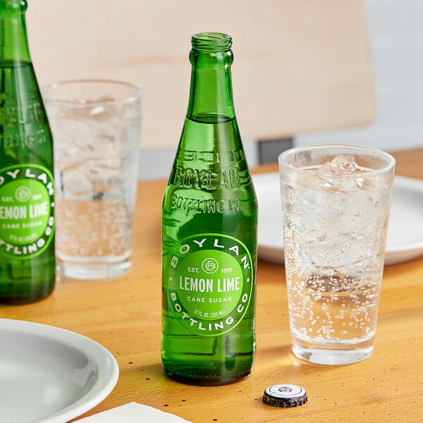 A close up of a green Boylan Bottling Co. Lemon Lime Soda bottle next to a glass of water.