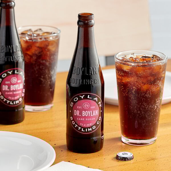 A close-up of a Boylan Soda bottle on a table next to a glass of ice and a plate.