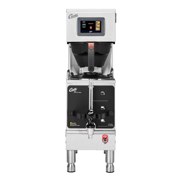 A stainless steel commercial coffee brewing machine with a digital display and control panel, featuring a large brew basket and spout for dispensing coffee.