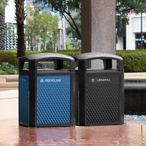 A blue Rubbermaid recycling panel on a black trash can next to a blue Rubbermaid recycling bin.