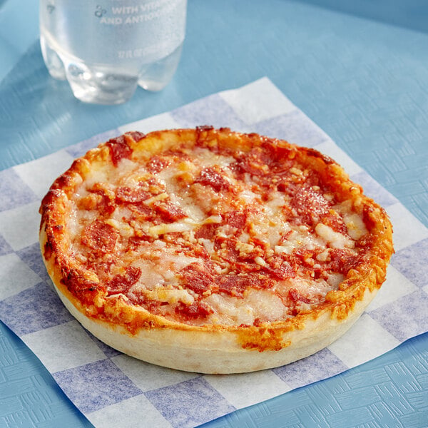 An individually wrapped Tony's deep dish pepperoni pizza on a checkered napkin.