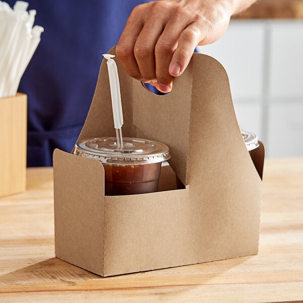 A hand holding a Choice drink carrier with cups of brown liquid.