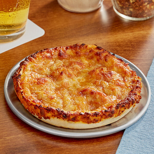 A Red Baron deep dish cheese pizza on a plate next to a glass of beer.