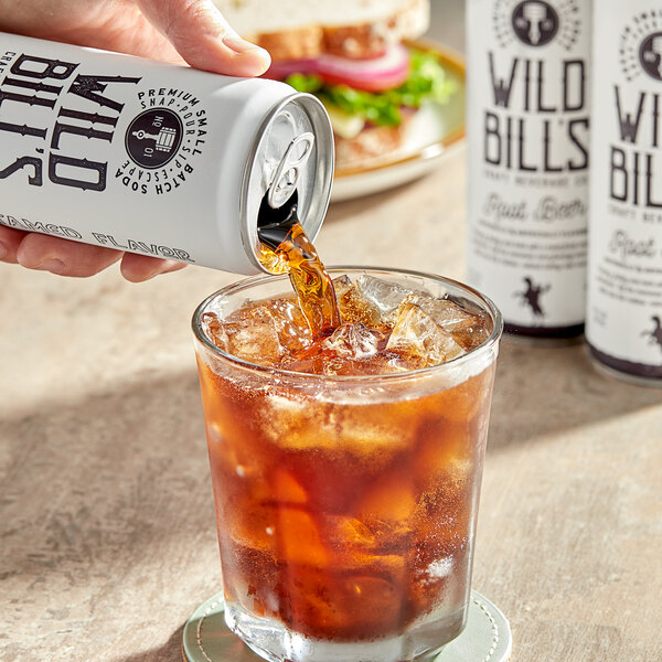 A hand pouring Wild Bill's Root Beer into a glass of ice.