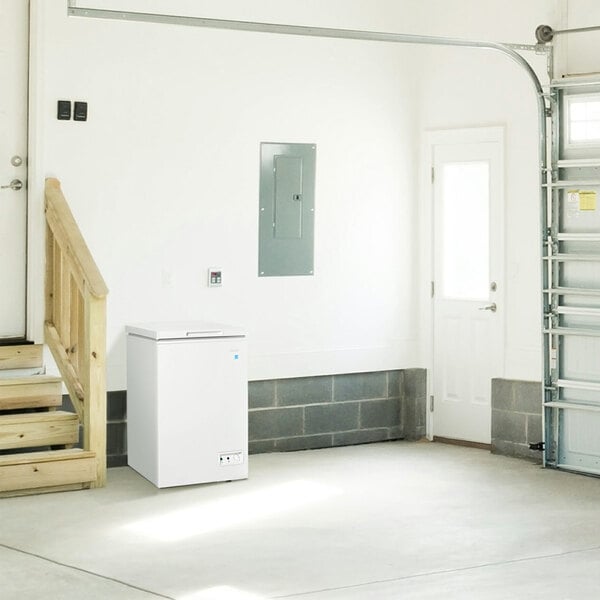 A white Danby chest freezer in a garage with the door open.