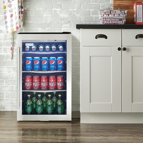 A stainless steel glass door beverage refrigerator with a towel bar handle, stocked with assorted drinks.