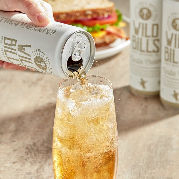A hand holds a can of Wild Bill's Vanilla Cream Soda with a white label.