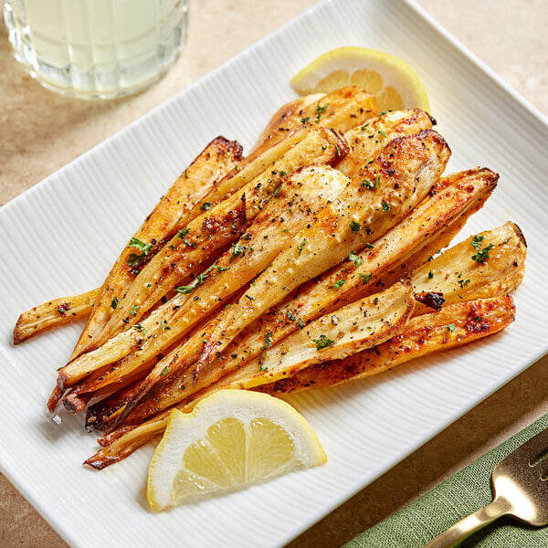 A plate of grilled parsnips with lemon wedges on a table in a farm-to-table restaurant.