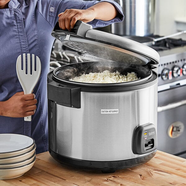 A woman using a Galaxy commercial rice cooker to cook rice.