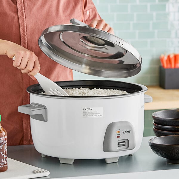 A person using a Galaxy commercial rice cooker to cook rice.