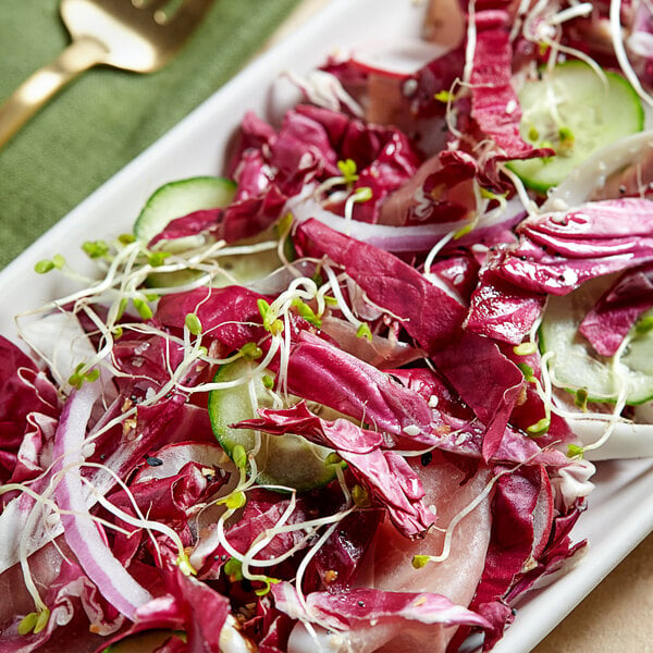 A salad on a plate with Fresh Radicchio, red cabbage, cucumber, and onions.