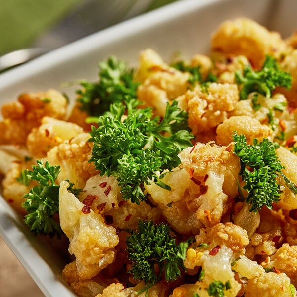 A bowl of cauliflower with fresh curly parsley on top.