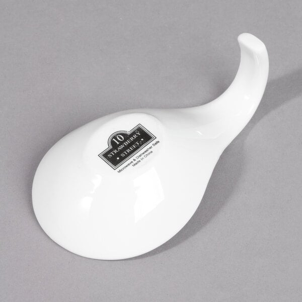 A white porcelain tapas spoon with a black logo.