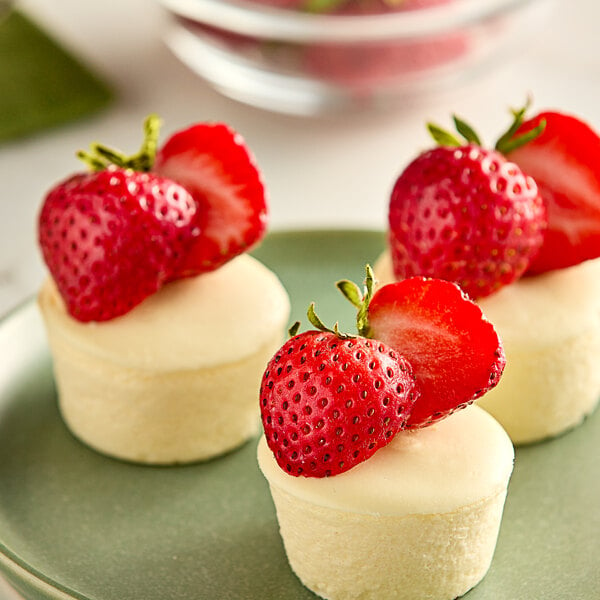 A group of three mini cheesecakes with strawberries on top.