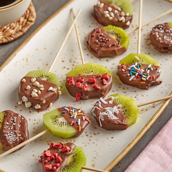 A chocolate covered kiwi fruit on a plate.