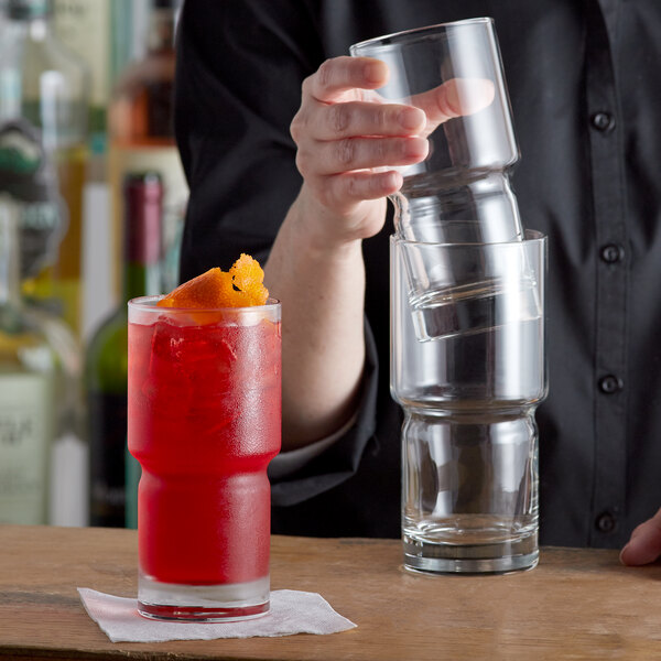 A person pouring a drink into a Libbey Newton beverage glass on a table.