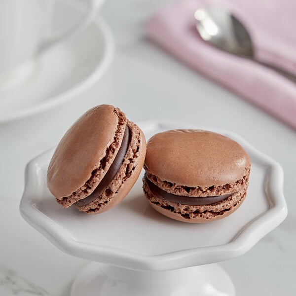 Two brown macarons on a white plate.