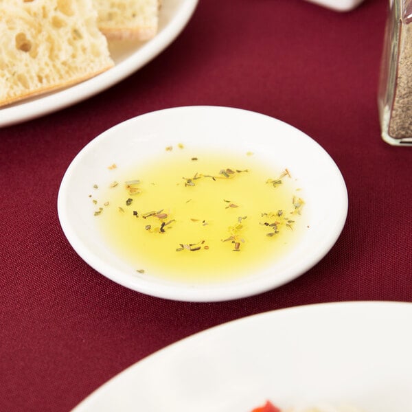 A Libbey Porcelana bright white round micro porcelain coupe plate with a piece of bread on it.