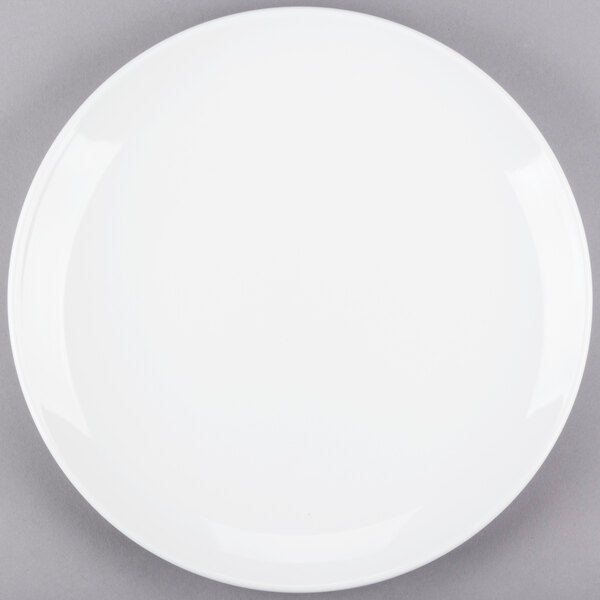 A Libbey Porcelana bright white round porcelain coupe plate on a gray surface.
