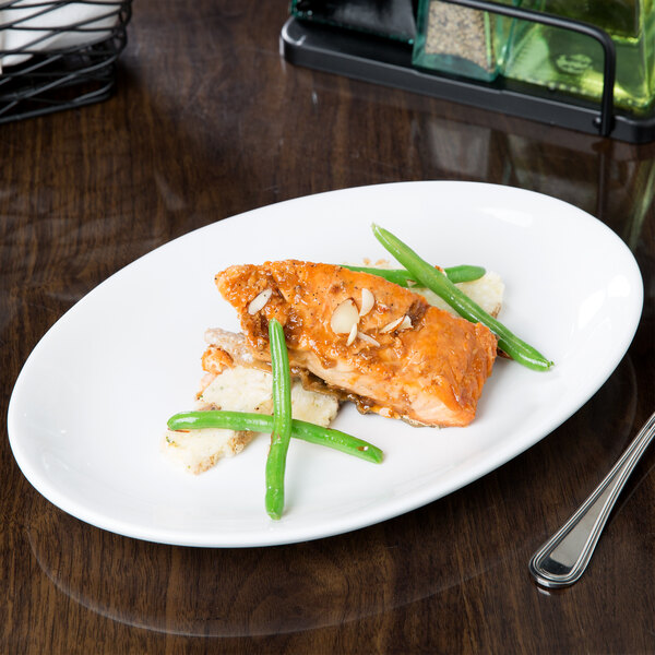 A Libbey bright white oval platter with food on a table.