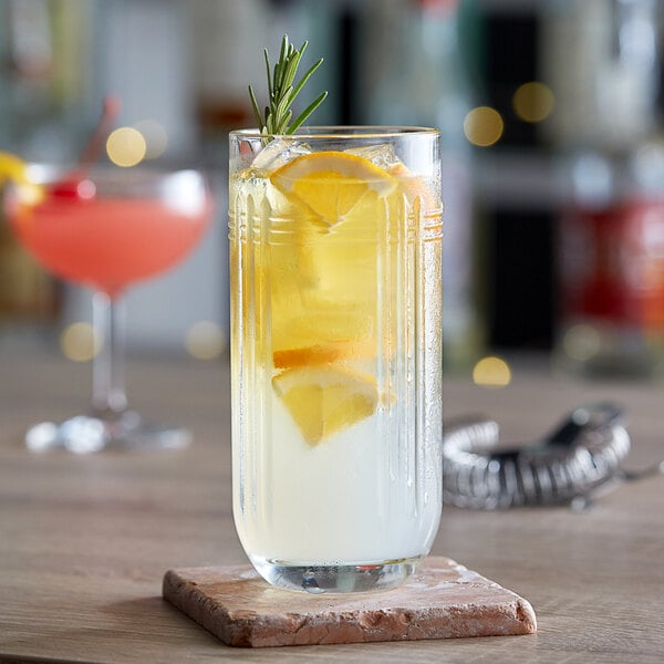 A Libbey highball glass with a lemon and white liquid on a stone coaster.