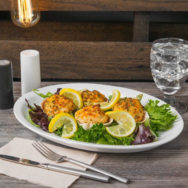 A Libbey Porcelana white oval platter with food and a lemon slice.