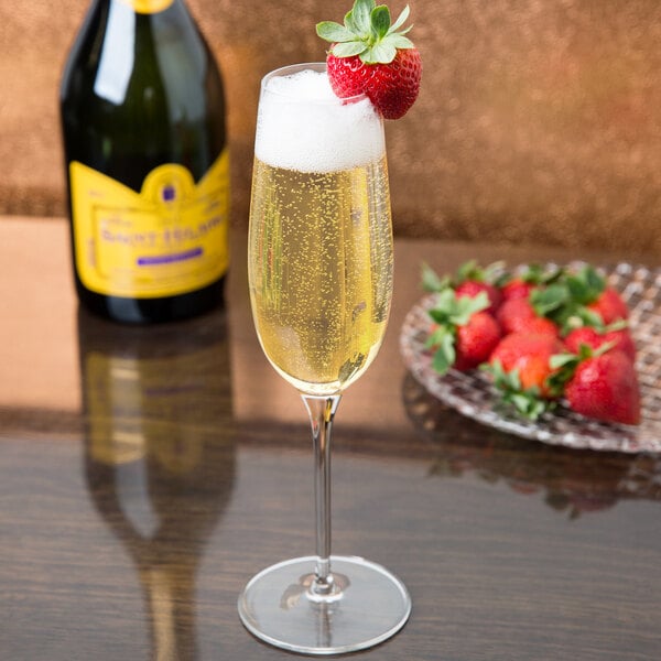 A Reserve by Libbey Renaissance champagne flute filled with champagne and a strawberry on the rim.