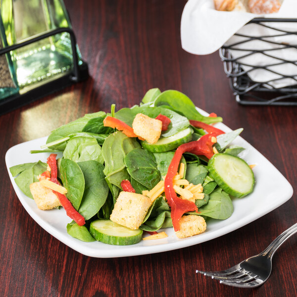 A Libbey Porcelana square coupe plate with a salad of spinach, peppers, and cheese.