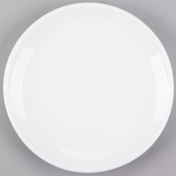 A Libbey Porcelana bright white round porcelain coupe plate on a gray surface.