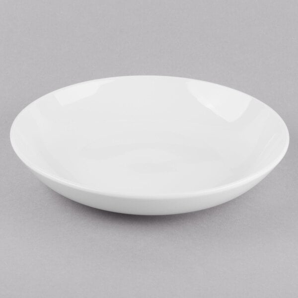 A Libbey Porcelana bright white porcelain low bowl on a grey surface.