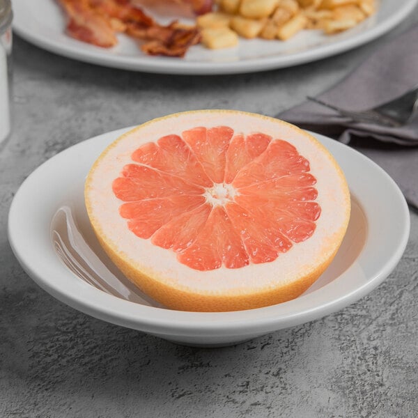 A Libbey Porcelana Bright White Porcelain grapefruit bowl with a half of a grapefruit in it.