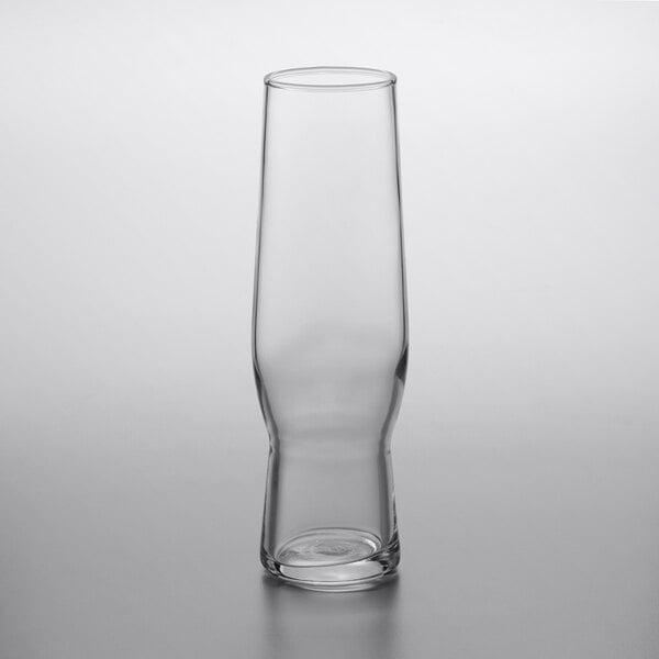 A Libbey clear flute glass with a small amount of liquid in it.