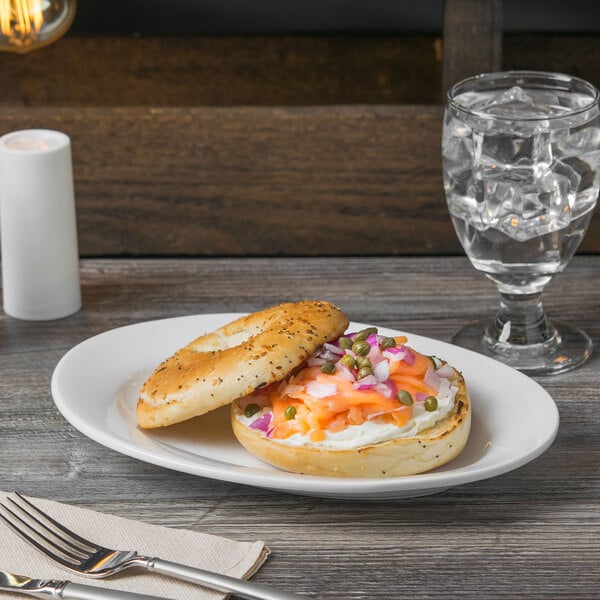 A Libbey white oval porcelain platter with a bagel sandwich on it.