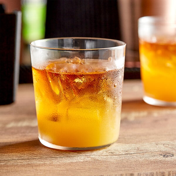 Two Libbey Cidra rocks glasses filled with orange drinks and ice on a wooden table.