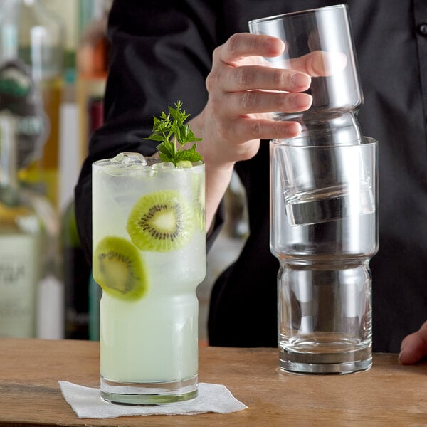 A bartender pouring a drink into a Libbey Newton stackable cooler glass.